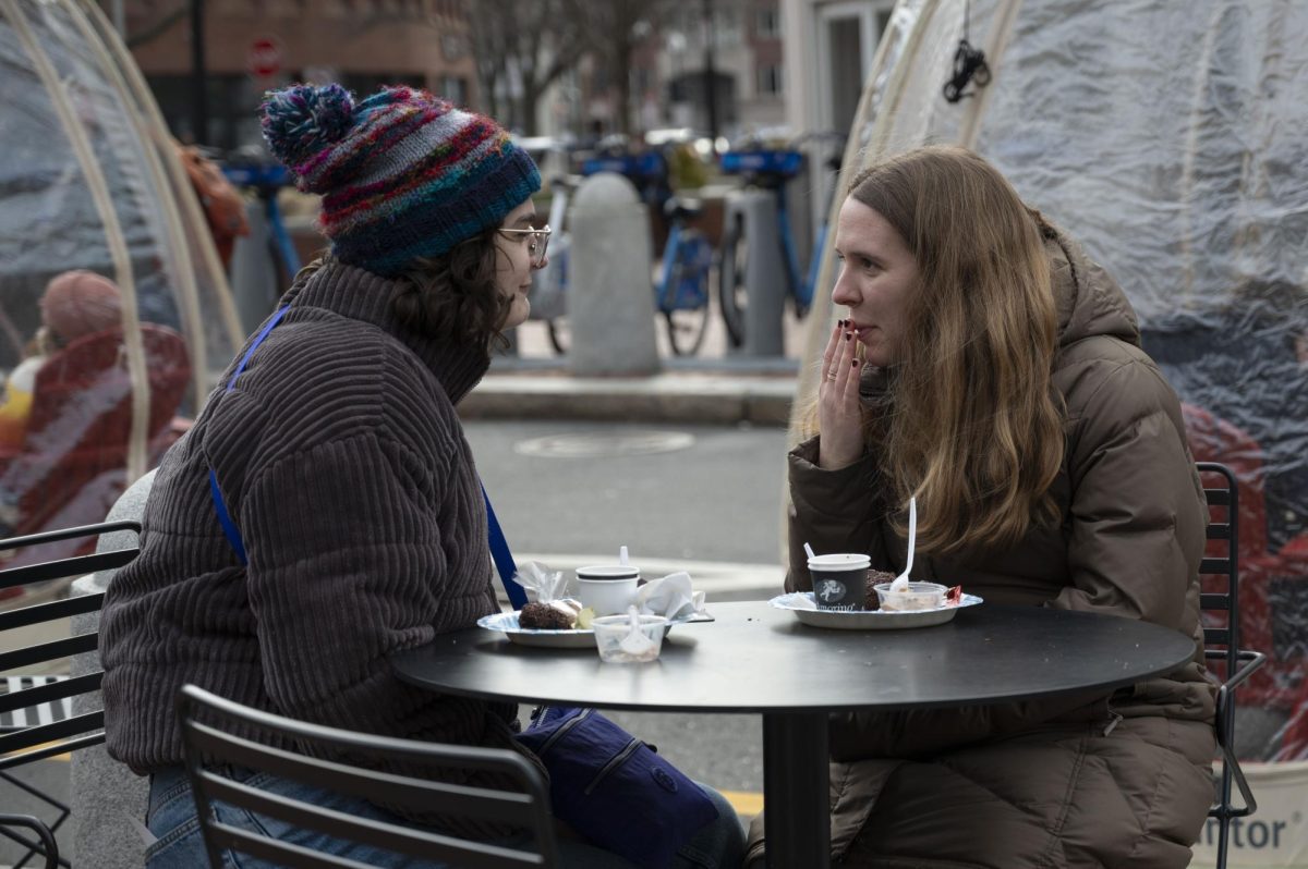 Two friends catch up while enjoying their plates of free chocolate samples. Along with outdoor tables and chairs, Brattle Plaza featured a few igloos that visitors could sit in for extra warmth.