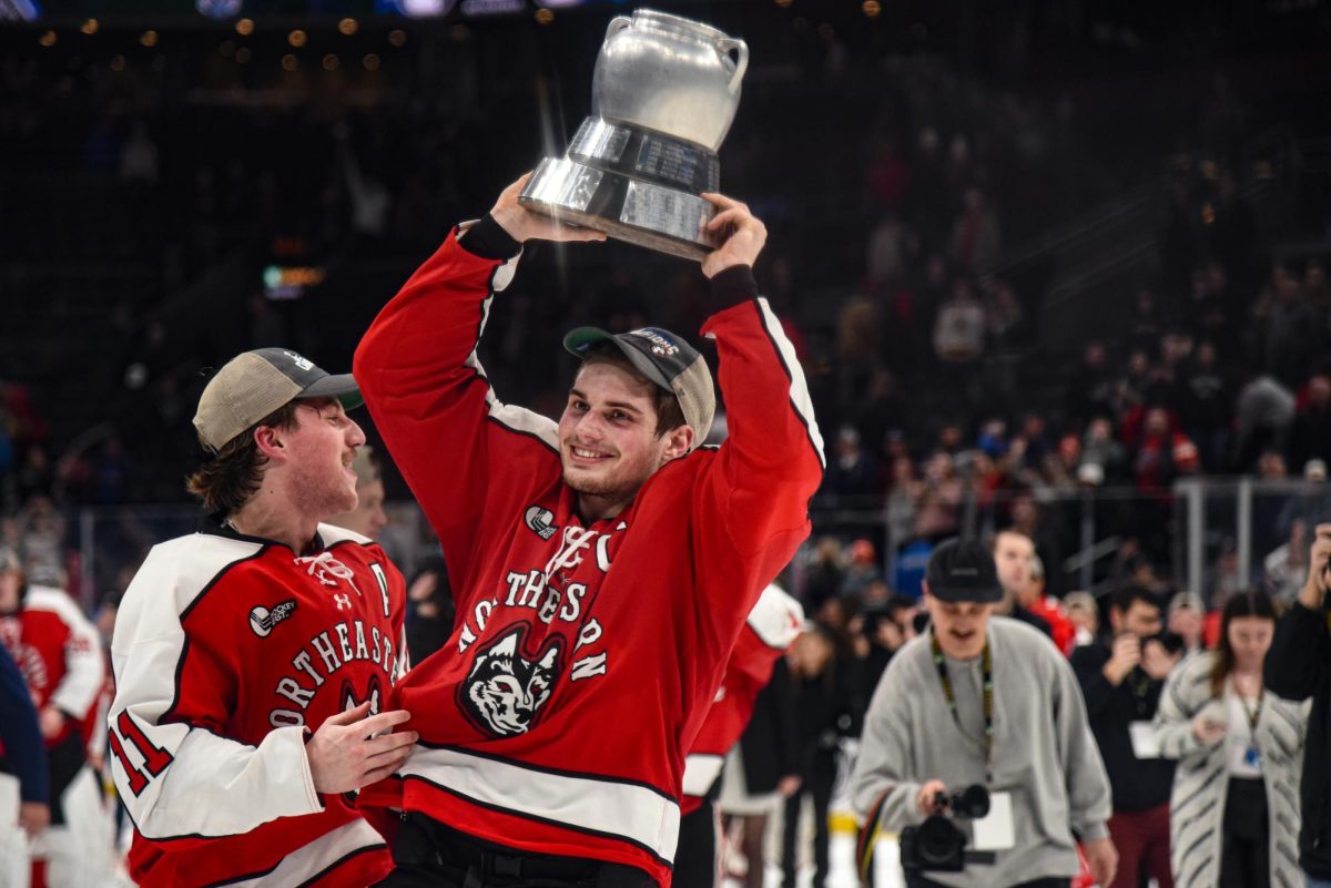 Captain Justin Hryckowian hoists the Beanpot trophy over his head. Northeastern defeated BU 4-3 in overtime in the 71st Beanpot tournament. 