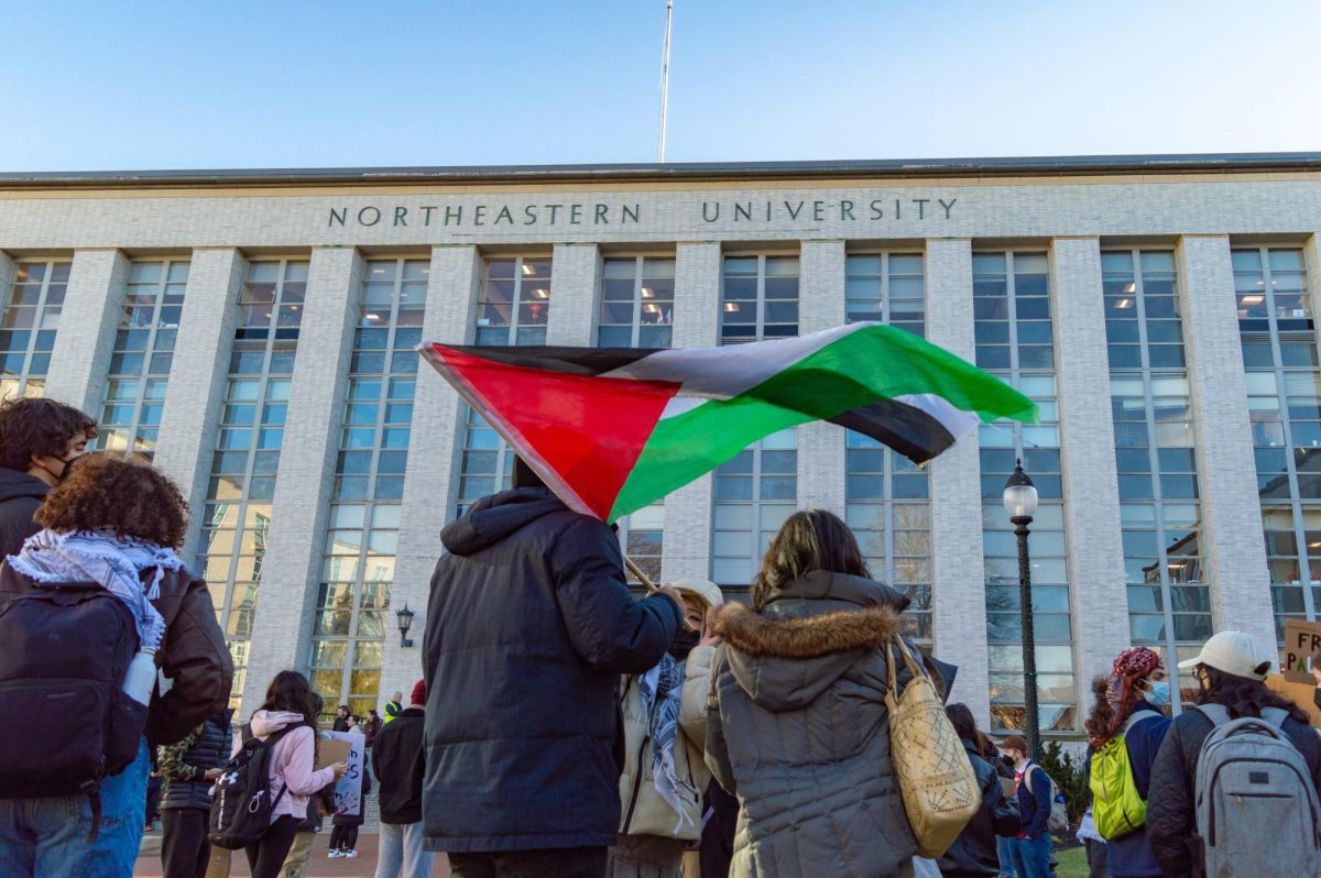 A protester holds a Palestinian flag in front of Ell Hall during a Huskies for a Free Palestine rally protesting the disciplinary charges against three students Jan. 10. In their responses to student protests, universities have tried to keep valued donors and ensure that students feel safe.