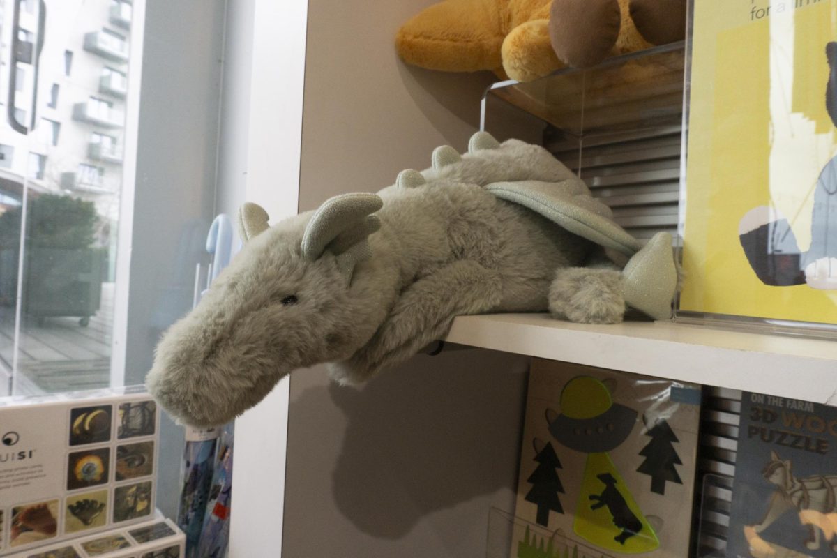 A lone dragon Jellycat leans over a shelf. Many large Jellycats were displayed by themselves.