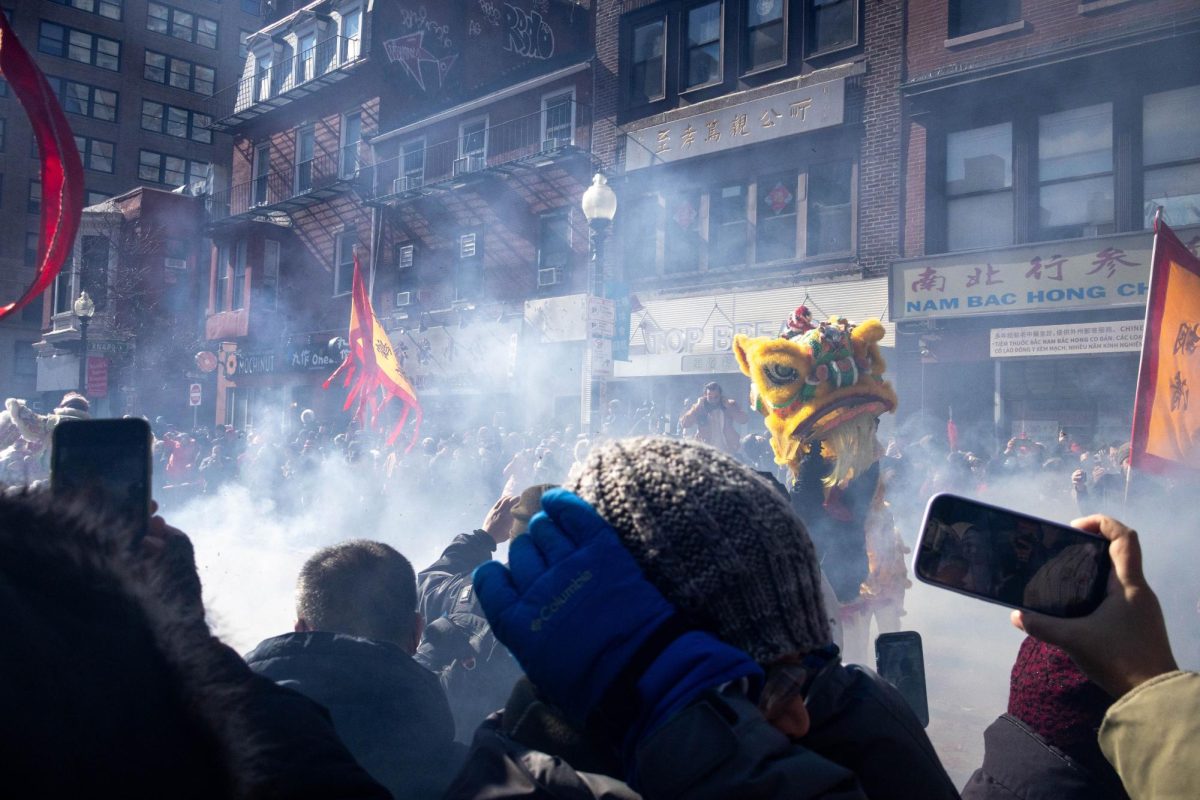 A crowd forms around a group of lion dancers as firecracker smoke fills the air. In Chinese legend, firecrackers warded off evil spirits and bad luck.