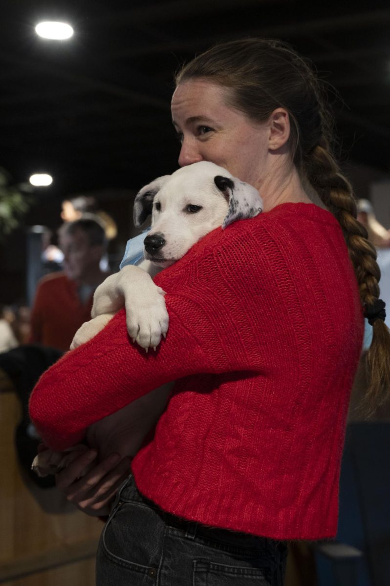 A potential adopter smiles while holding a sleepy puppy in her arms. People and puppies alike were grateful for the socialization the event provided.