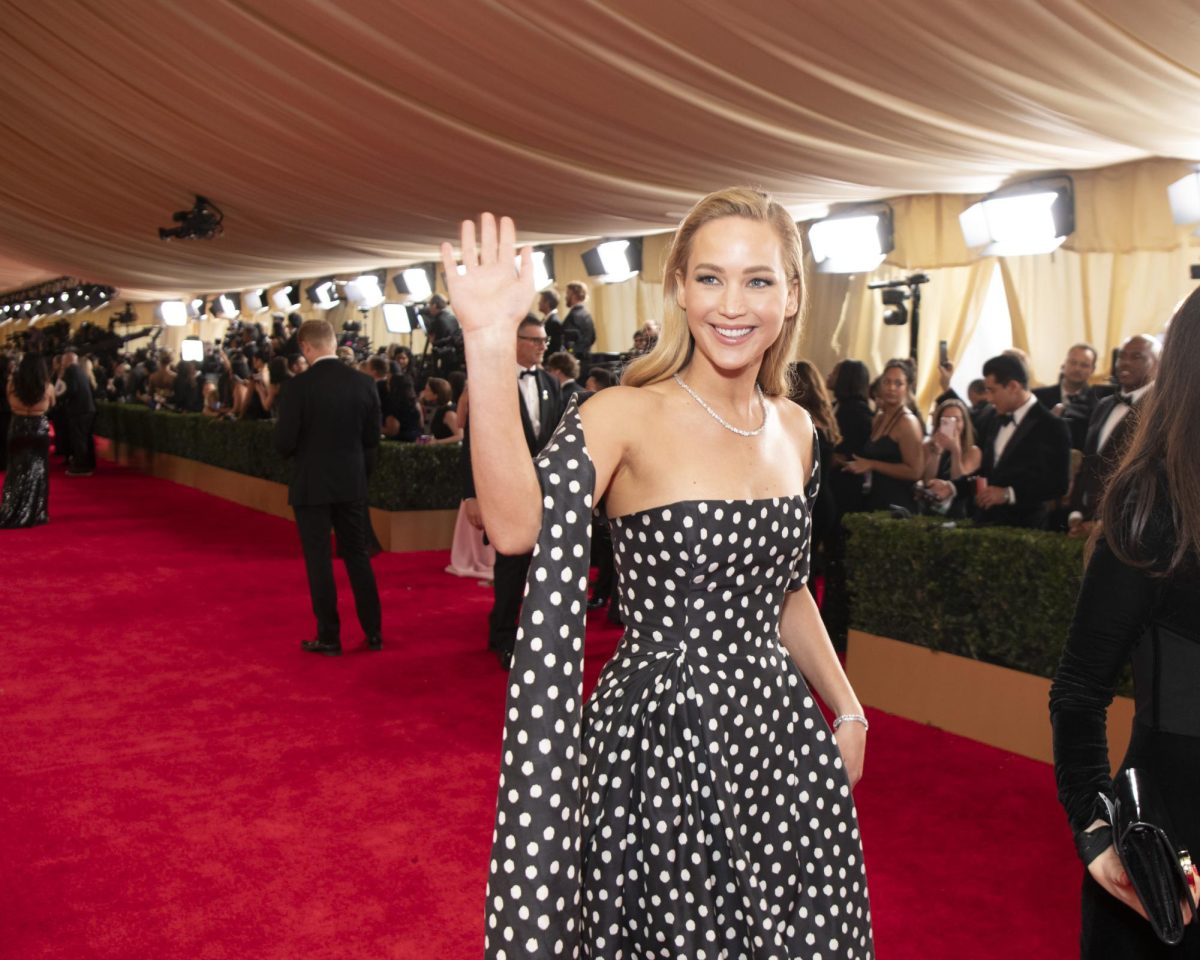 Jennifer Lawrence walks the red carpet, waving. Her striking Dior dress was one of the evenings best. Photo courtesy Jenny Anderson, Disney.