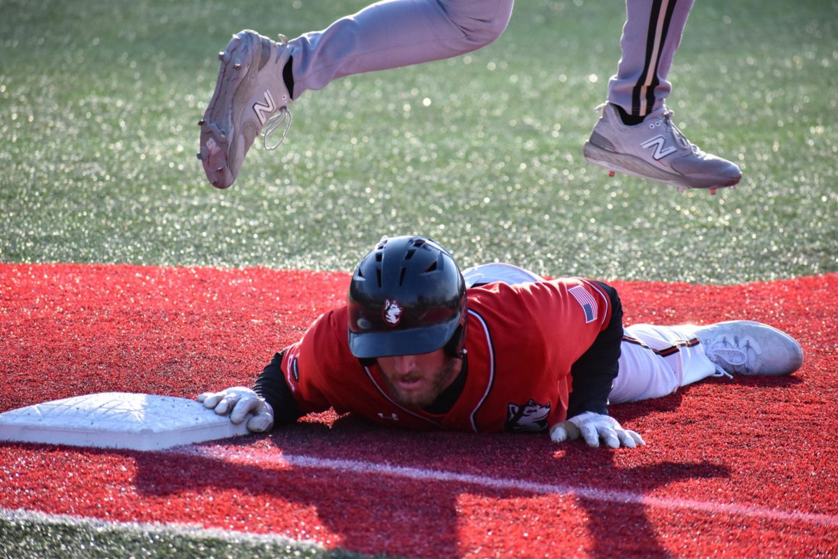 A Northeastern baseball team player dives for the base during a game against Bryant University March 13.