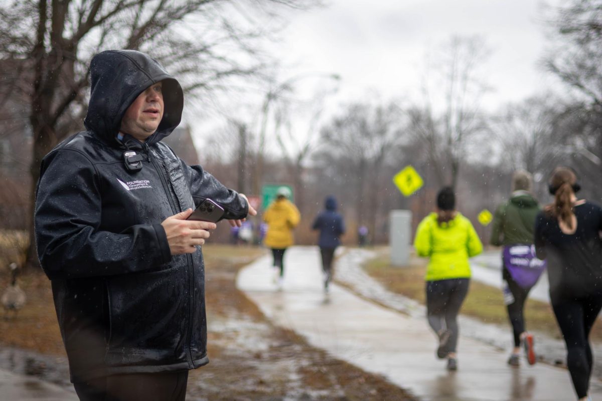 An event volunteer directs runners to the finish line. Along the course, police details and officers blocked roads and sidewalks to protect runners who had yet to complete the course.