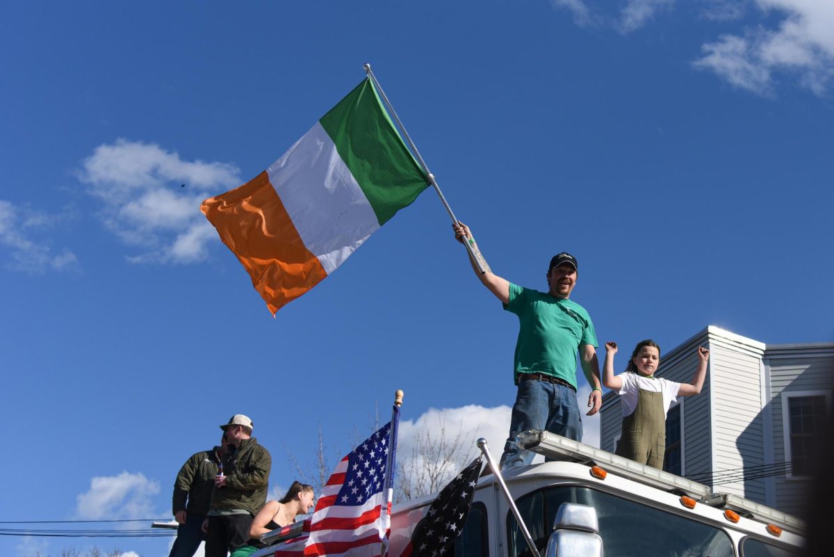 A man waves an Irish flag while standing on a fire truck. The St. Patricks Day parade has been a South Boston tradition for over 120 years.