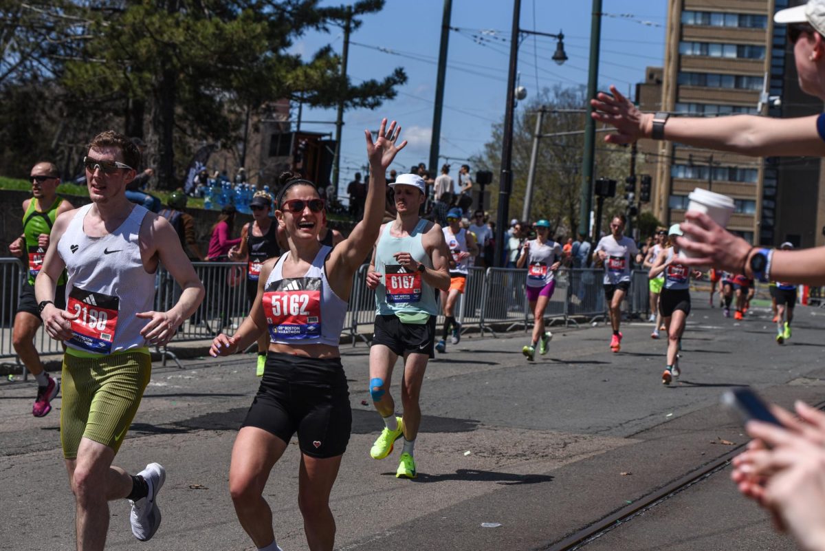 Kylie Cardoso smiles and waves to a spectator as she makes her way down Chestnut Hill Avenue during the last couple miles of the marathon. Chestnut Hill Avenue was a dedicated spectator zone in Brookline along with Cleveland Circle and the Chestnut Hill Reservoir.