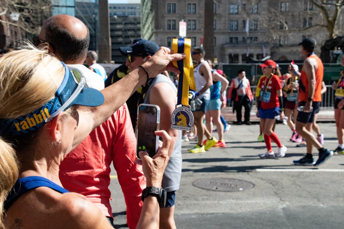 A participant snaps a photo of their marathon medal. The Boston Marathon mascot, a unicorn nicknamed Spike, could be found on the medallion and inspired runners to be as elusive as a unicorn. 