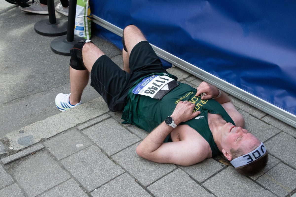 Joseph Anderson lies on the ground, catching his breath after completing the marathon. Participants received blankets, water, snacks and a spot in the shade to rest post-race.