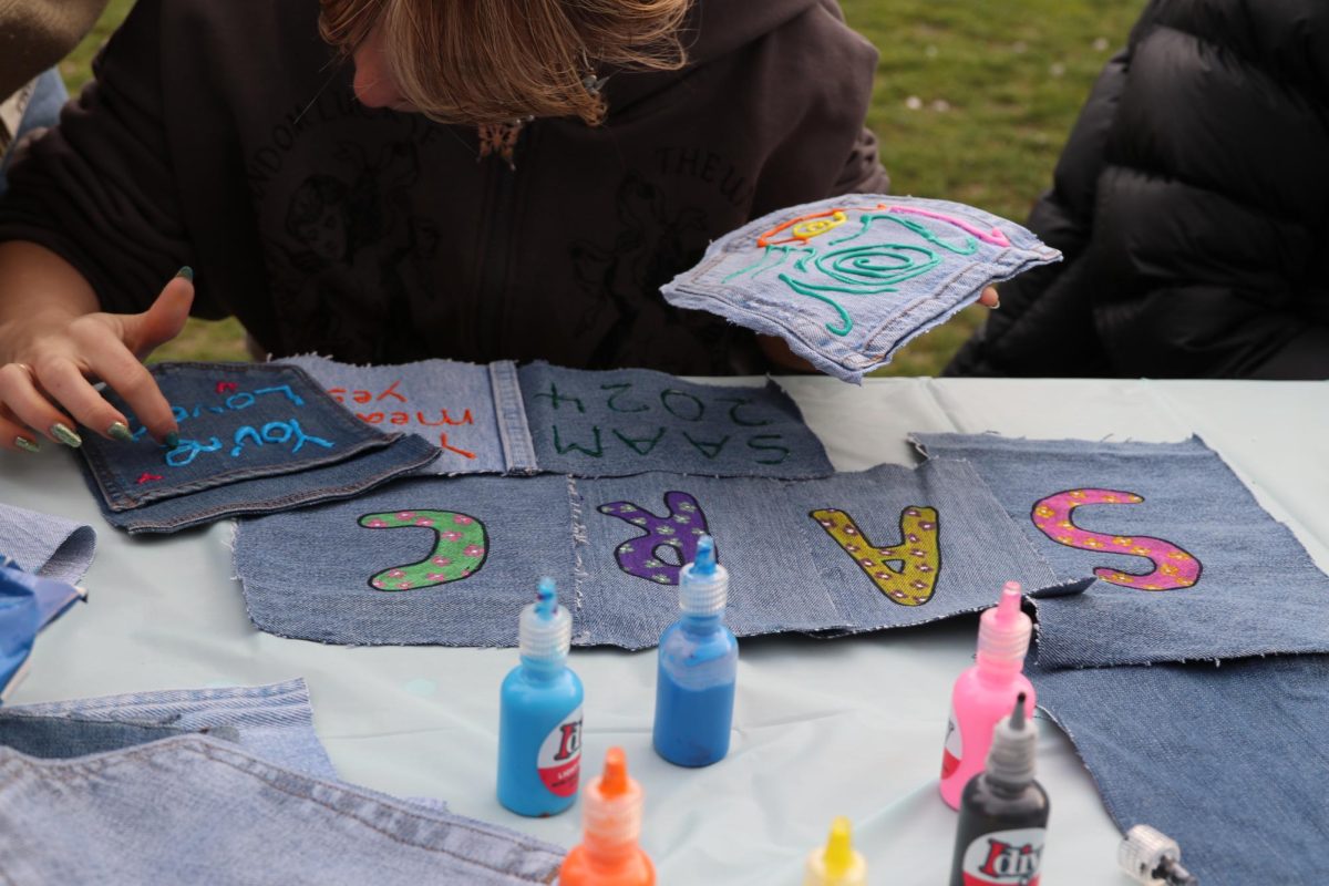 An event attendee uses puffy paint to decorate denim pieces during SARC’s Take Back the Night event April 17. Read more here.