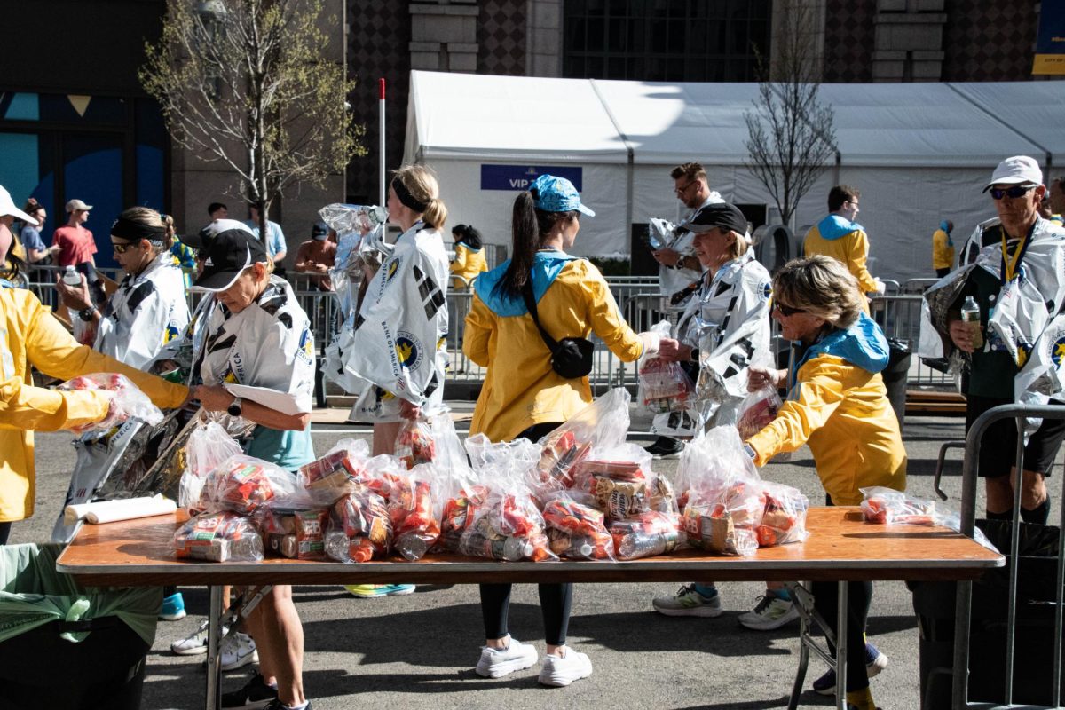 Marathon volunteers hand out bags of snacks and water bottles to runners. Around 9,000 volunteers help make the marathon run smoothly each year.