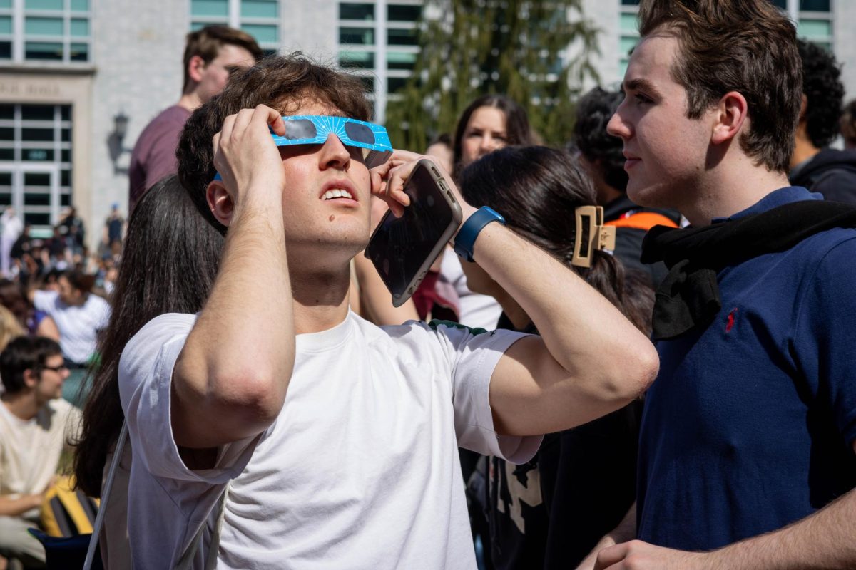 A student looks at the solar eclipse through eclipse glasses. Read more here.