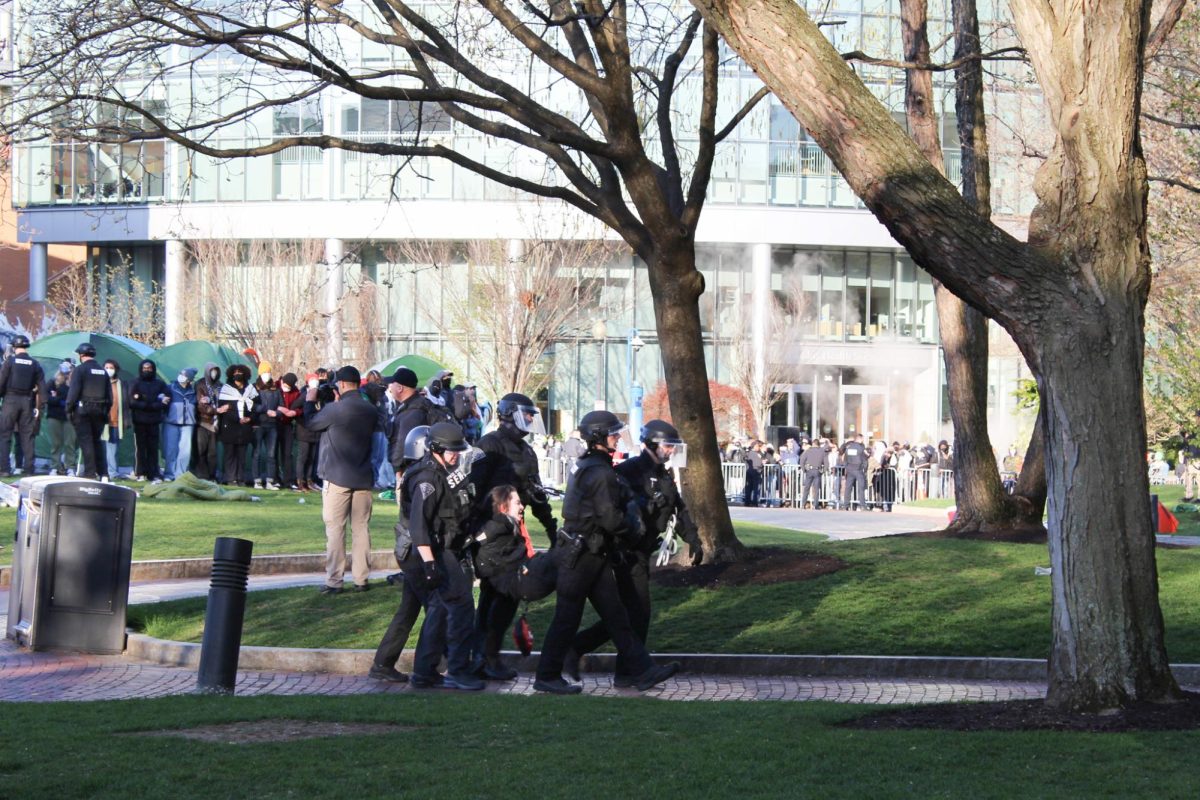 Police arrest and escort a demonstrator who participated in the encampment to Shillman Hall. Arrests began at 7 a.m. and 100 people have been detained according to statements from HFP and the university.




