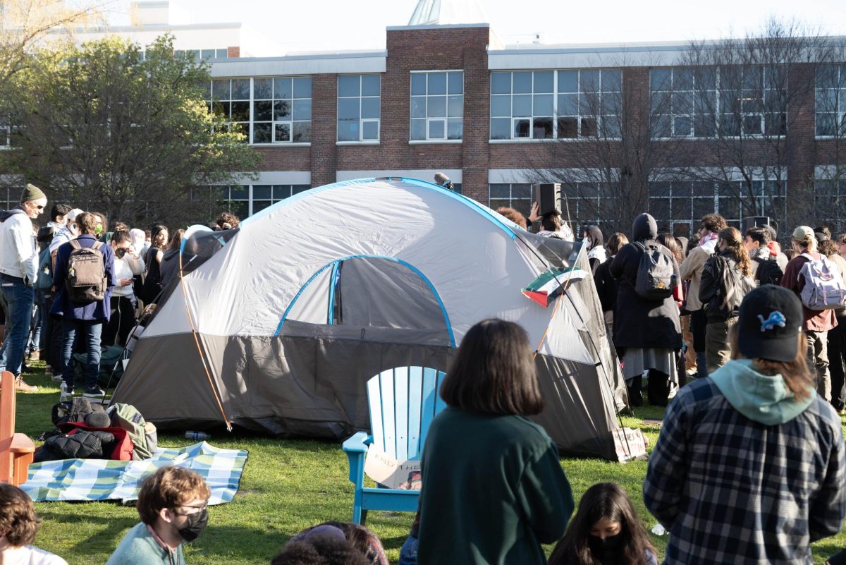 Protesters gather next to an encampment tent for an informational meeting from HFP. The meeting included announcements of a catered dinner and a Passover Seder later that night.