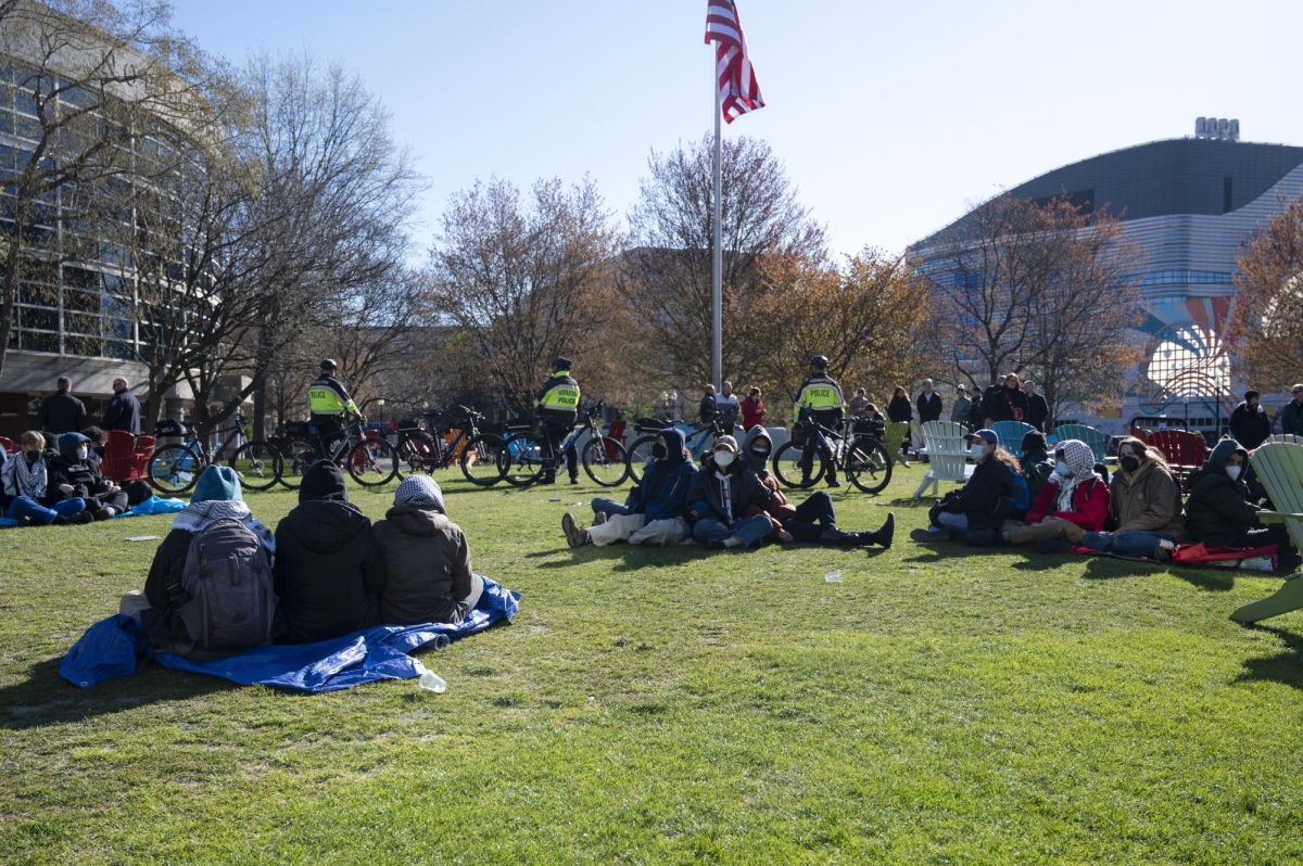 Pro-Palestine student demonstrators gather in Centennial Common while surrounded by a barricade of bikes, Adirondack chairs and police officers. Students sat in small groups, linking arms and chanting pro-Palestine slogans.