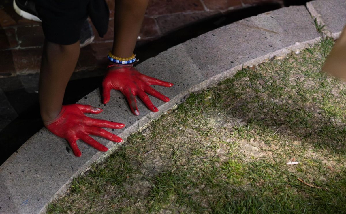 A pro-Palestine protester paints the curb with red hand prints. HFP did not endorse the hand prints and instructed people making hand prints to stop.