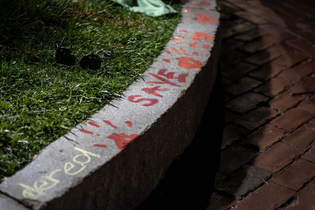 Red hand prints, chalk and the word save decorate the curb near Centennial Common. Pro-Palestine demonstrators covered the sidewalks in chalk imploring Northeastern to divest. 