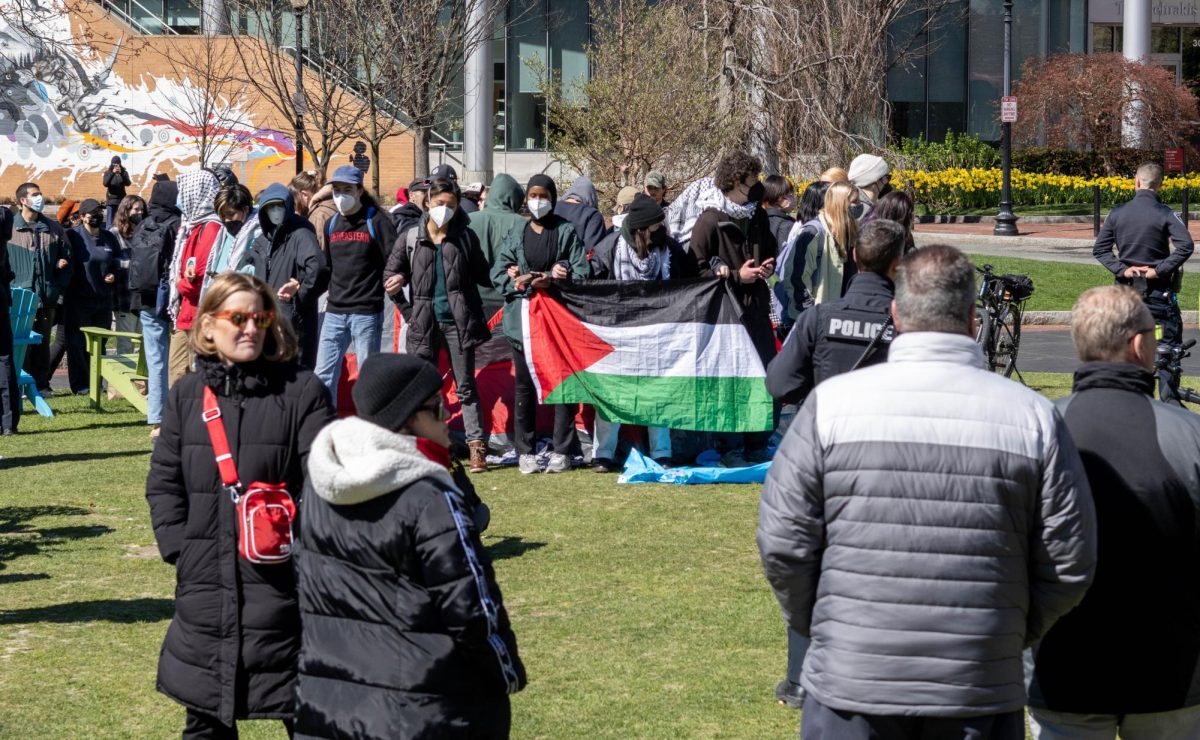 Pro-Palestine student protestors encircle a tent and link arms while chanting around 9:45 a.m. Students took turns taking breaks in the tent and sharing snacks before returning to chanting.