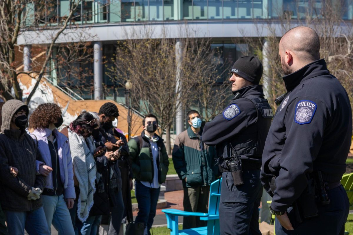 Two NUPD officers watch protesters at Centennial Common. A student said that Northeastern's police presence at the protest is part of a nationwide trend.