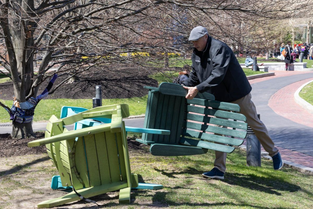 A Northeastern staff member removes chairs from Centennial Common. Around noon, Northeastern police and staff moved chairs from the perimeter of Centennial to in front of the concrete structure at the front of the Common.