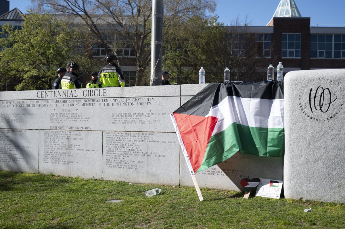 A Palestinian flag is held down by water bottles on the Centennial Common ledge.