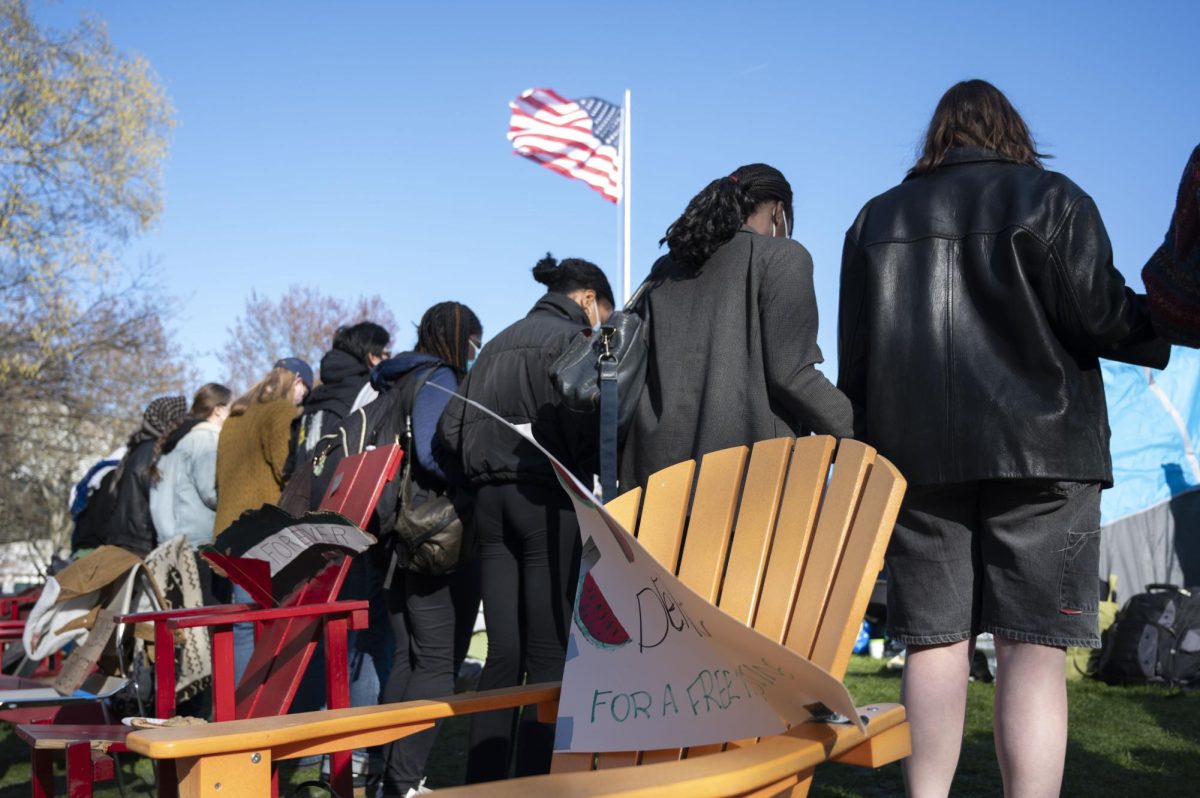 Students hold hands while circling Centennial Common.