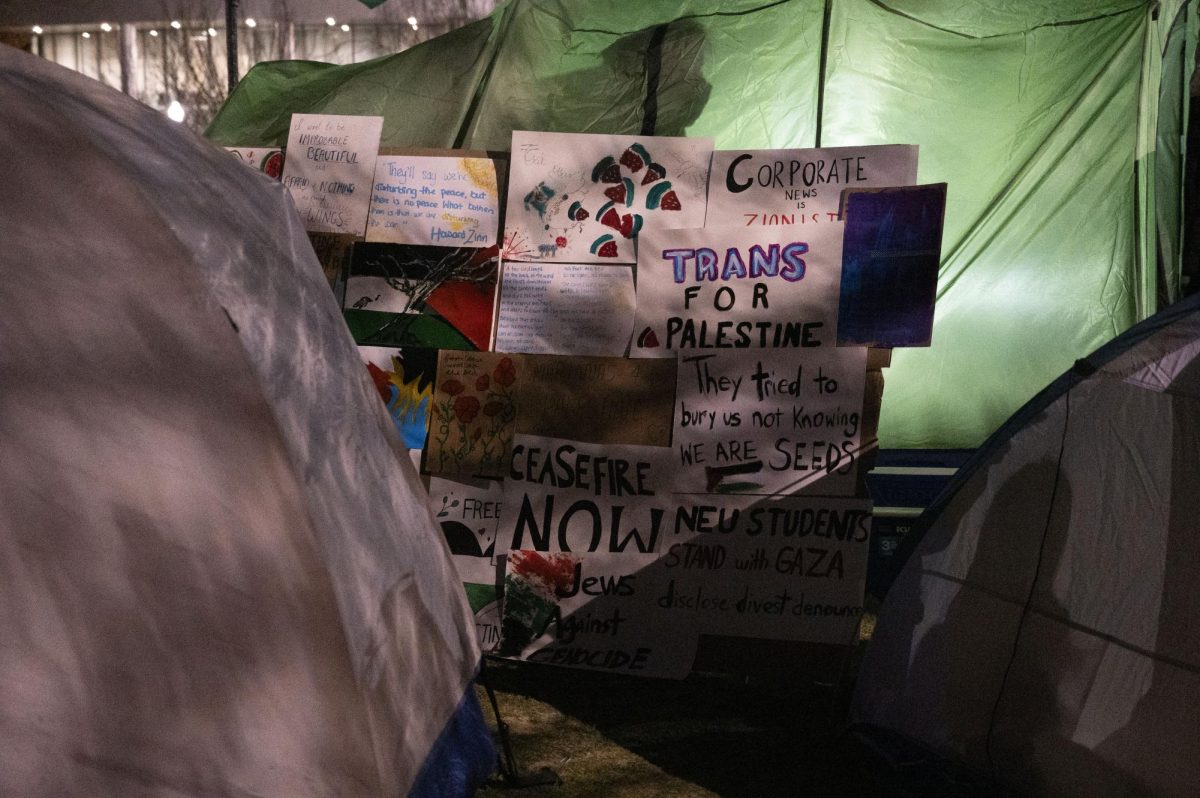 A collage of pro-Palestine posters leans against a tent. 