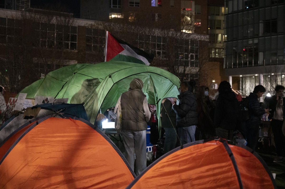 Pro-Palestine protesters gather near a tent in the center of the encampment. 