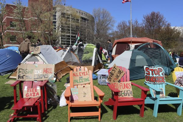 Cardboard signs sit on chairs surrounding the encampment. Protesters made signs earlier this morning.