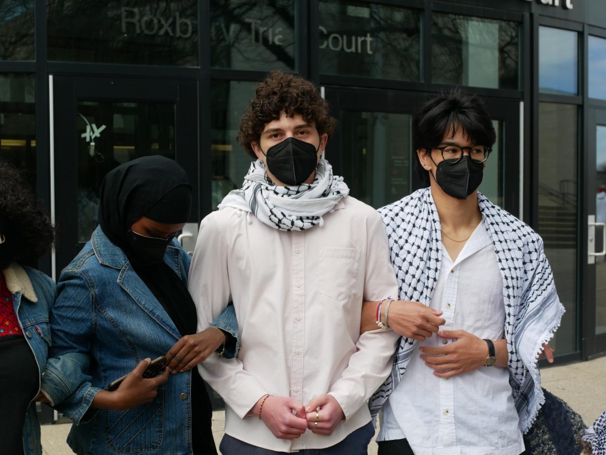 Kyler Shinkle-Stolar (center) stands linking arms with Sahra (left) and August, two other student protesters who were arrested for their involvement in the Centennial Common encampment. Shinkle-Stolar’s trespassing charges were dismissed during an arraignment April 29 at Boston Municipal Court in Roxbury.