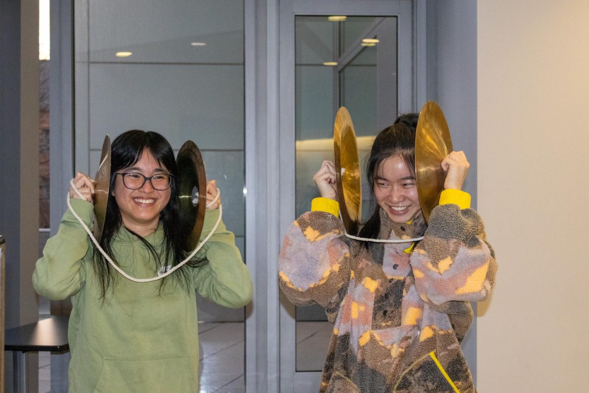Two members of the Dragon & Lion Dance Troupe have fun with their instruments at practice March 29. While practicing the troupe’s music, members joked around and enjoyed the vibrations of banging their cymbals together.