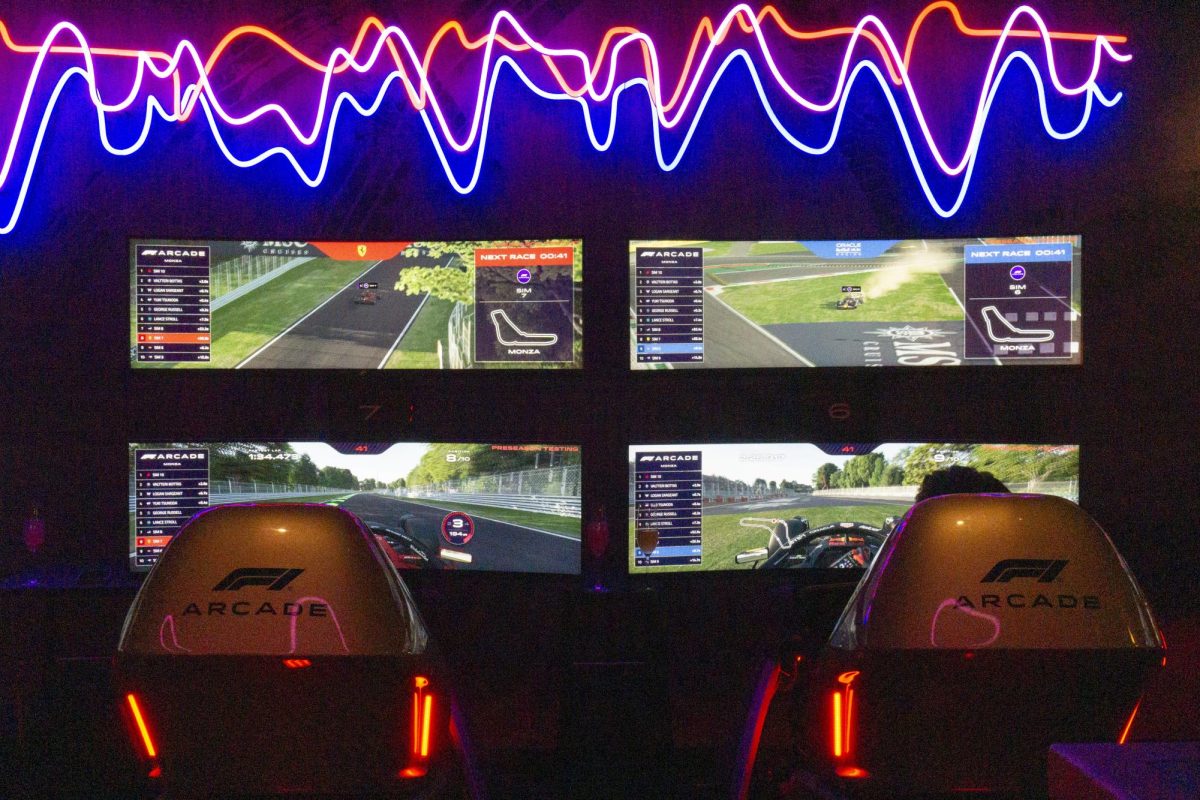 Two friends race head-to-head on Ferrari (left) and Red Bull simulators. Each simulator was designated a F1 team car and track chosen at random.