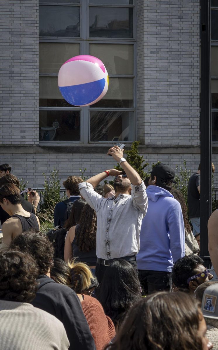 A student prepares to hit a beach ball into the crowd gathered at Krentzman Quad. While waiting for the eclipse, students enjoyed activities such as passing around a beach ball, playing music, picnicking and chatting with friends. 