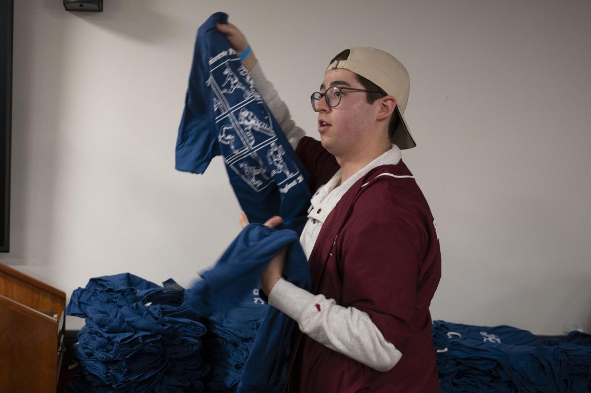 Benjamin Wise, a first-year business administration major and an external operations, or ExOp, coordinator for CUP, picks up T-shirts from a pile to hand out. Along with free apparel and accessories, CUP had free stickers available.