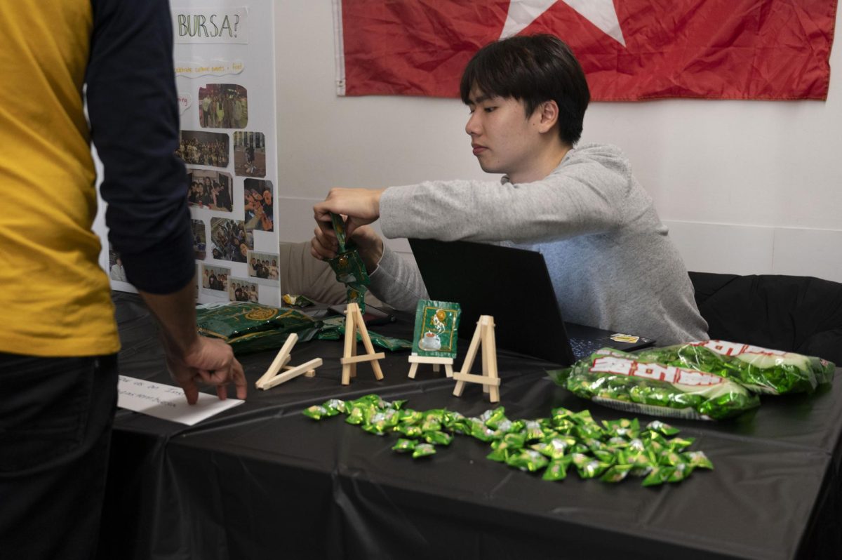 A member of Northeastern’s Burmese Student Association breaks up a pack of tea mix packets. Multiple organizations at the cultural fair handed out snacks from various countries.