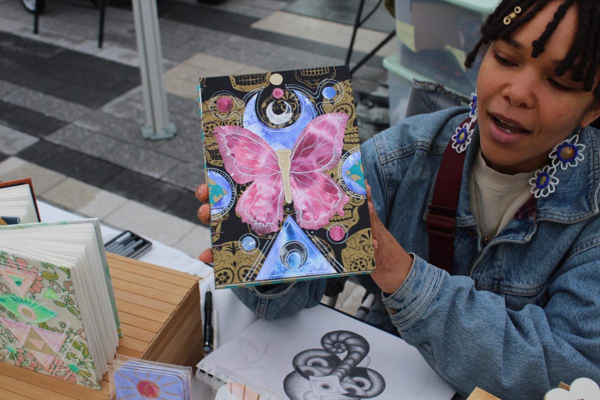 Mayté Castillo holds up a journal that she created with a butterfly design at the Seaport x Black Owned Bos. Market May 19. Read more here.