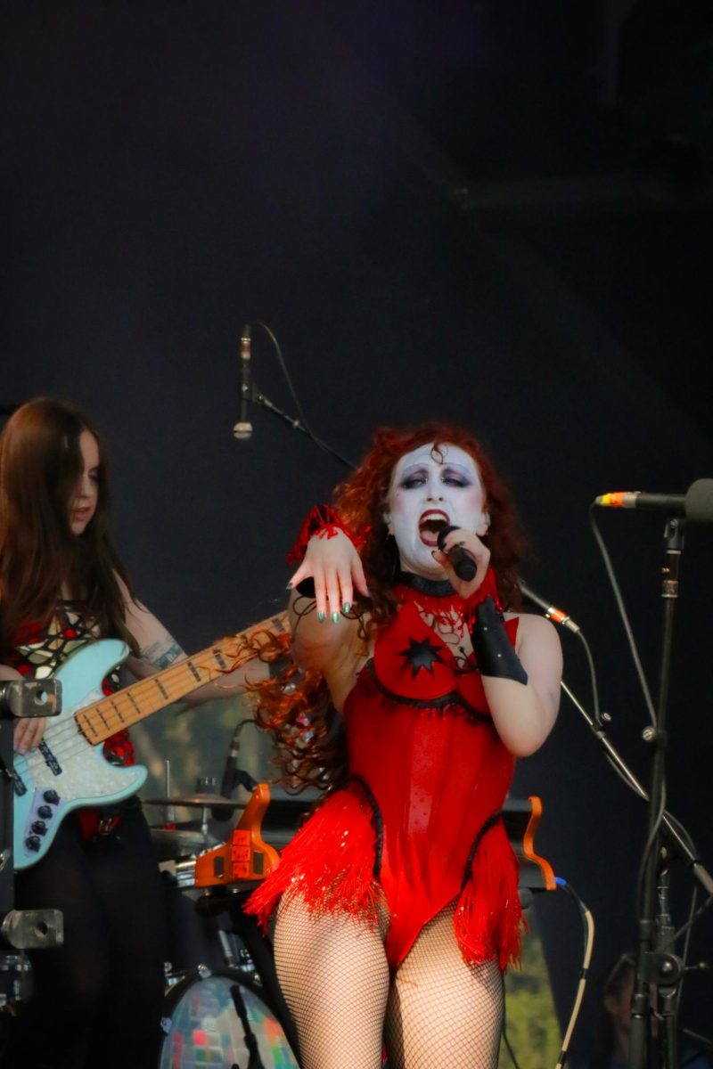 Roan holds her right hand out toward the audience during her performance. Roan was joined by three band members, including bassist Allee Fütterer (left).