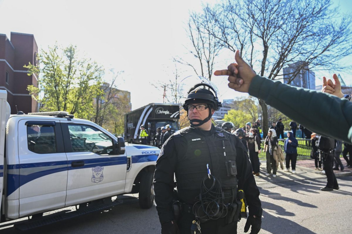 A protester gestures their middle finger at a BPD officer as BPD cars begin leaving campus. Protesters on both sides of Leon Street chanted and shouted as BPD officers left.