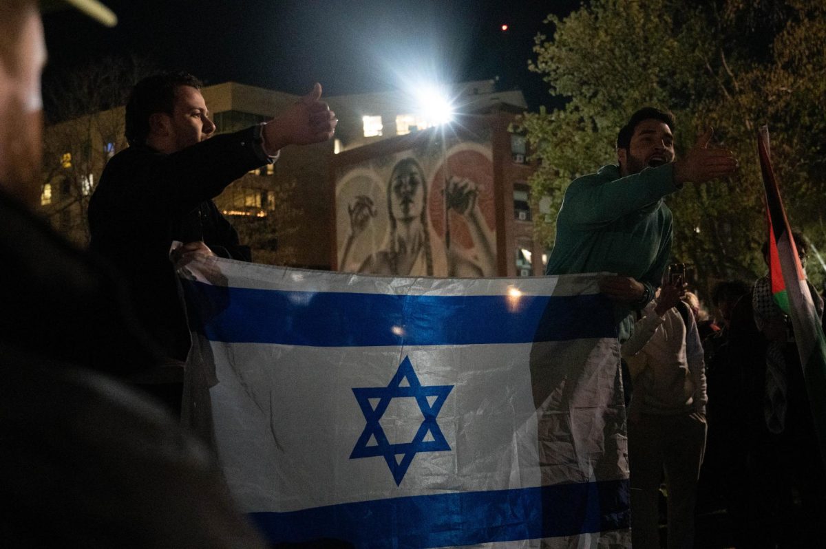 Two pro-Israel counter protesters hold up an Israeli flag while motioning toward pro-Palestine protesters. Over 200 people were estimated be on Centennial as pro-Israel and pro-Palestine protesters clashed at 11:30 p.m.