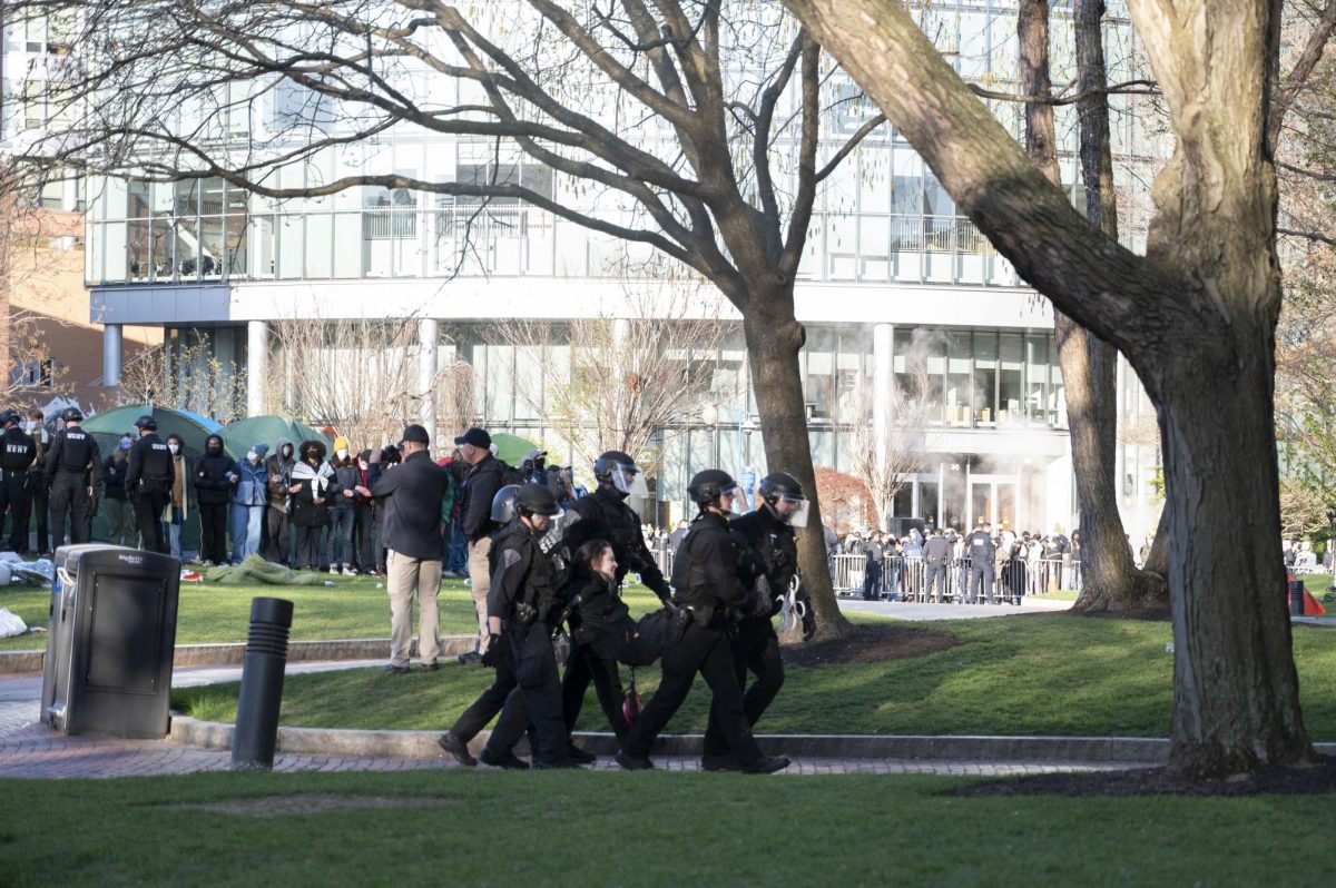 Police carry an arrested protester to Shillman Hall. Police in riot gear began making arrests at 7 a.m.