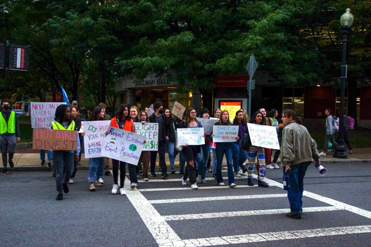 Activists+hold+signs+while+crossing+Forsyth+Street+during+a+DivestNU+protest+against+Northeasterns+investments+in+fossil+fuels+Oct.+15%2C+2023.+Many+Northeastern+students+joined+DivestNU+and+Sunrise+Northeastern+to+become+more+involved+in+climate+activism.+File+photo+by+Erin+Fine.