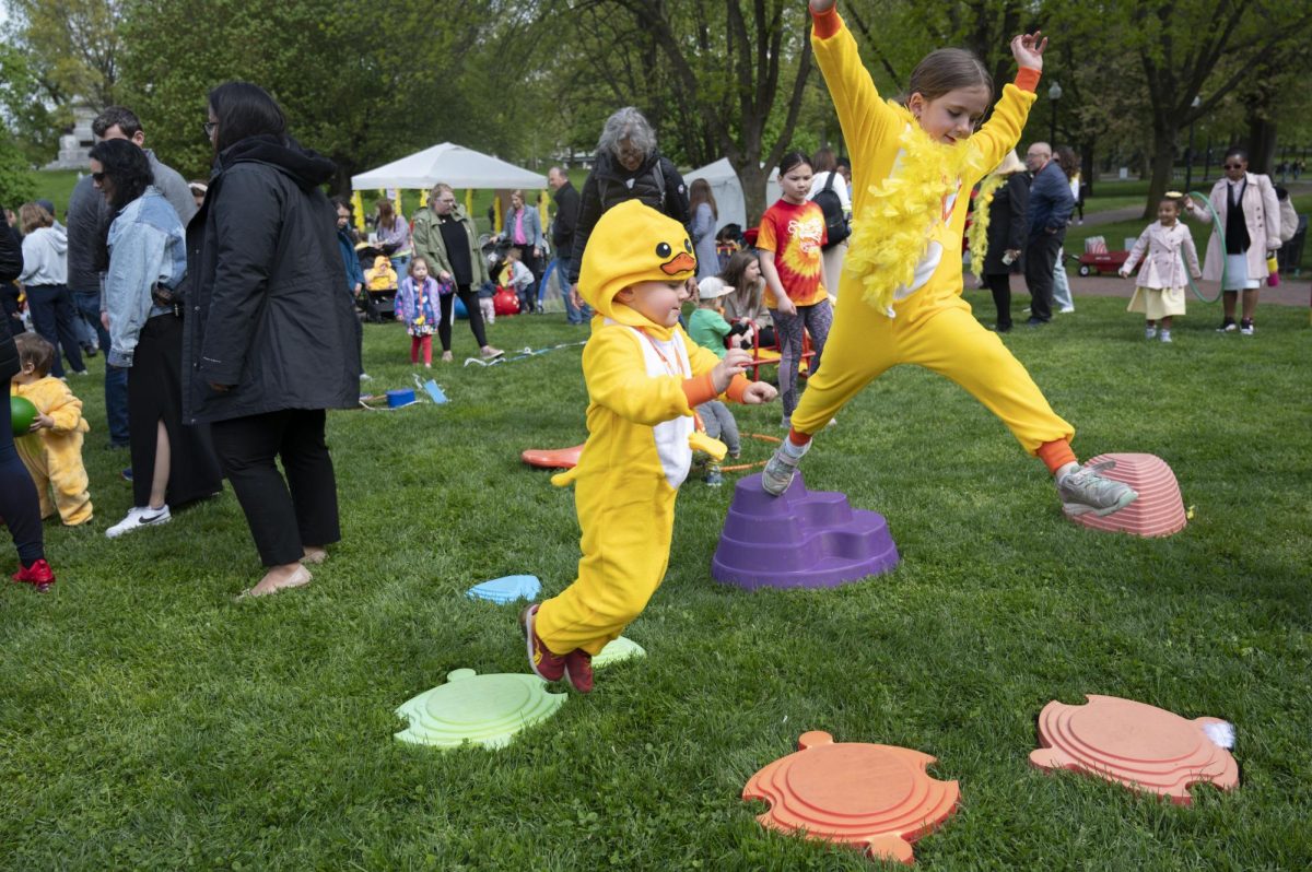 Two children dressed as ducklings hop from one plastic platform to another. Children wore yellow boas, jackets, tutus and more for Duckling Day.