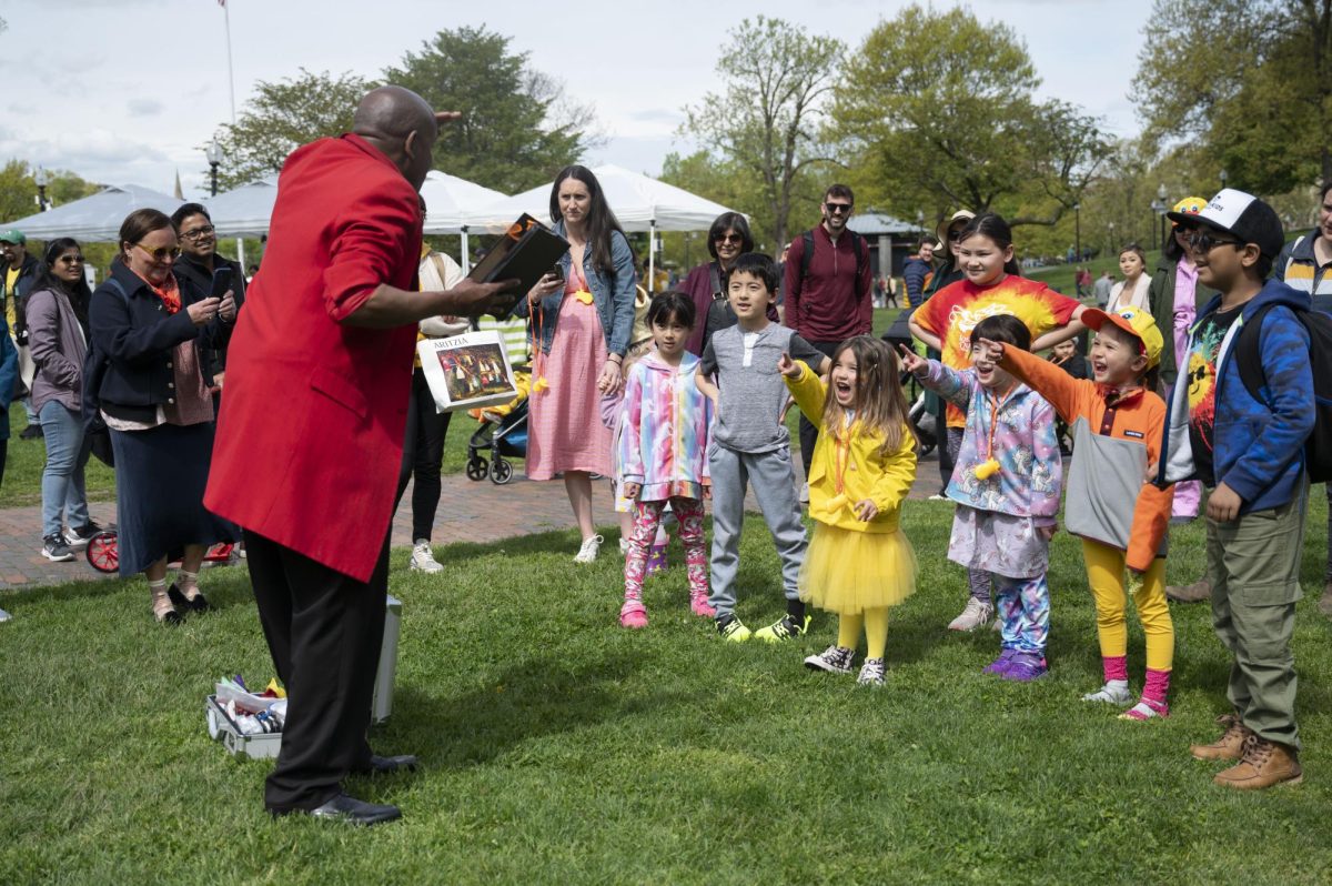 A group of children point and scream at a magician holding a flaming book. The magician brought a briefcase of various magic items around the Common, quacking kids up as he performed his tricks.