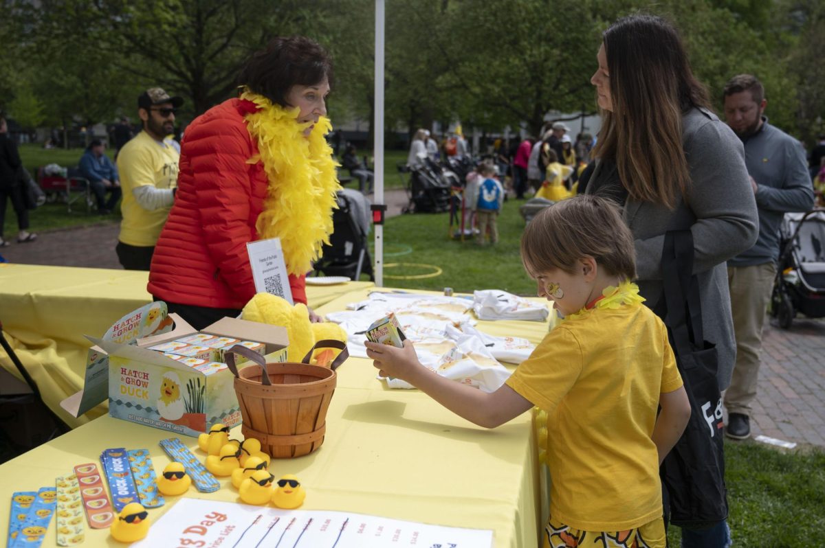 A Duckling Day participant picks up and examines a Hatch & Grow Duck toy. The event’s merchandise stand, called The Quack Shack, sold various items including T-shirts, bucket hats and backpacks.