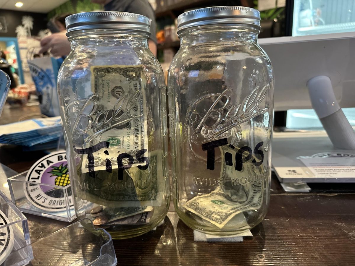 Two tip jars sit next to the register in Playa Bowls on Huntington Avenue. Various circumstances related to the COVID-19 pandemic created changes in tipping culture within the country.