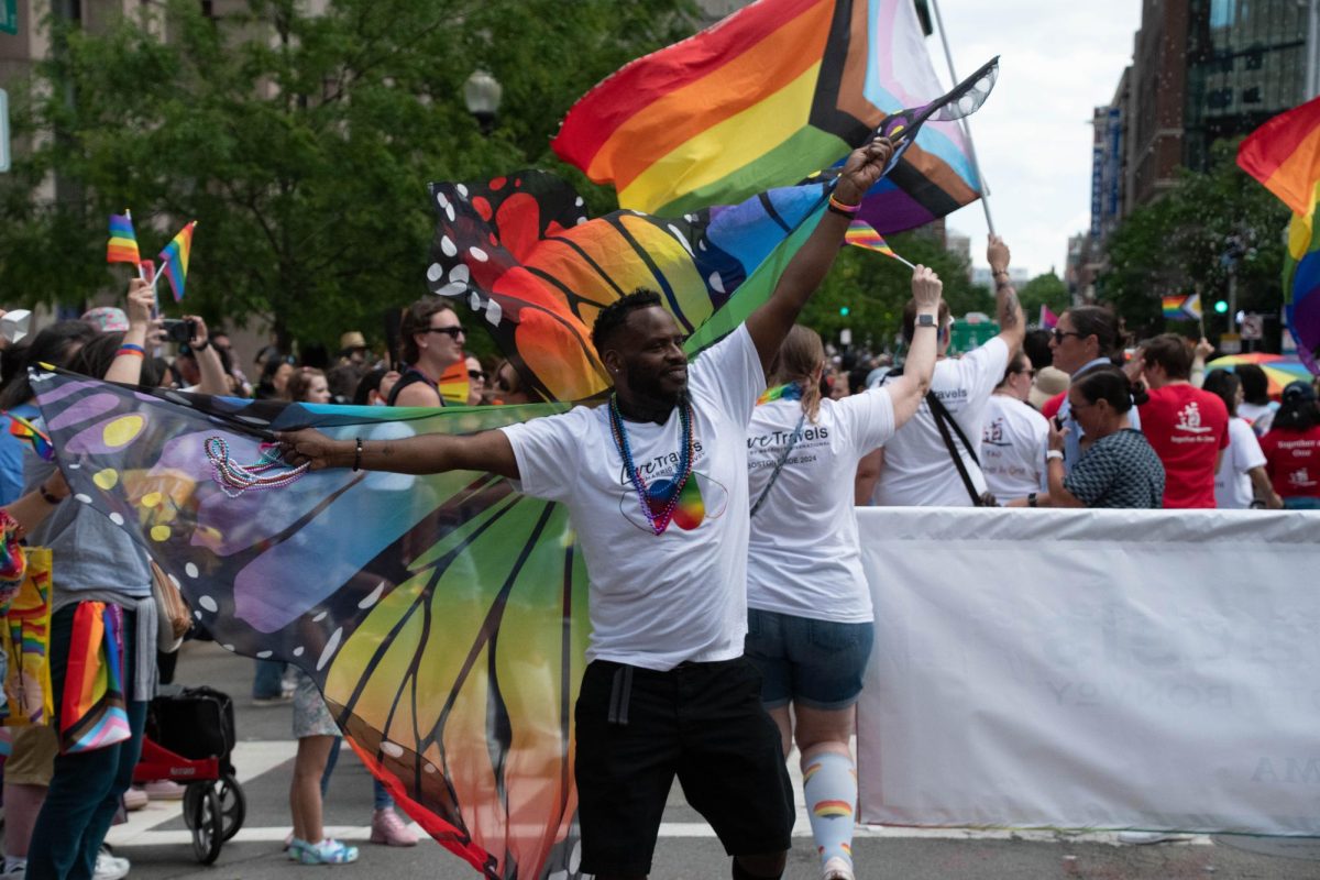 A man dances while holding rainbow butterfly wings.
