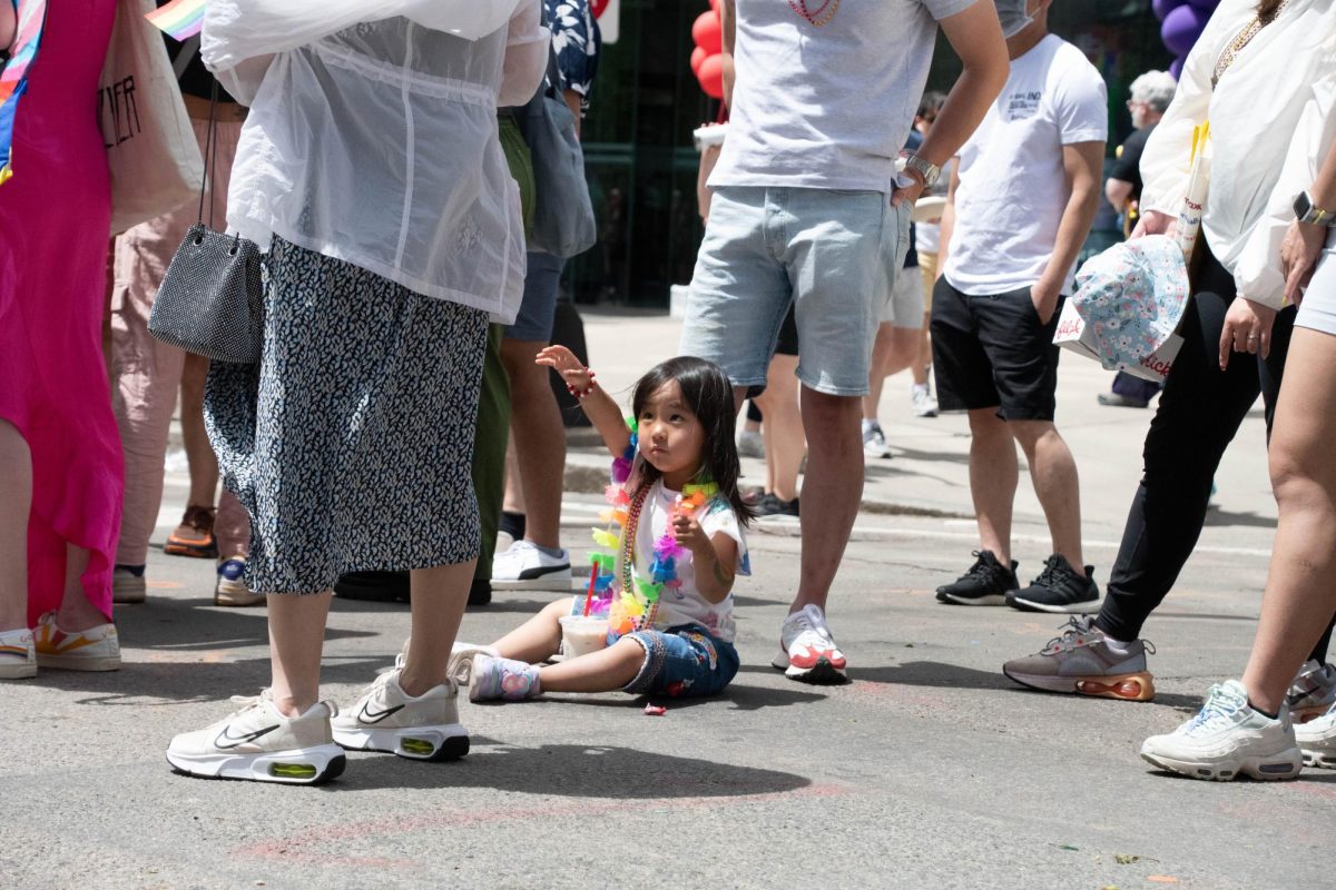 A child wearing a rainbow lei reaches for their mother.