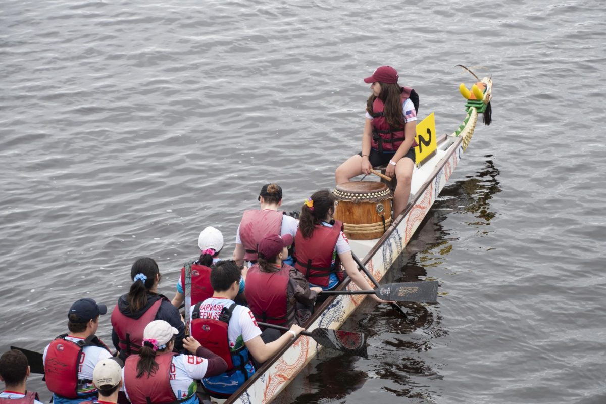 A rowing team slowly moves toward the dock following a race. Each team had a steersperson, who maneuvered the boat from the back using a large oar, and a drummer, who sat at the front and drummed to direct the stroke timing for paddlers.