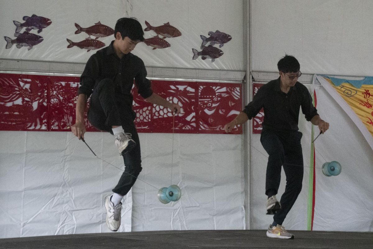 Two members of the Greater Boston Chinese Cultural Association perform Chinese yo-yo tricks. Tricks included jump roping, swinging and tossing blue yo-yos attached to strings.