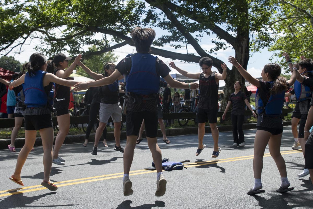 A boating team does jumping jacks prior to competing in the festival. Many teams stretched and practiced a rowing motion with their arms to warm up.